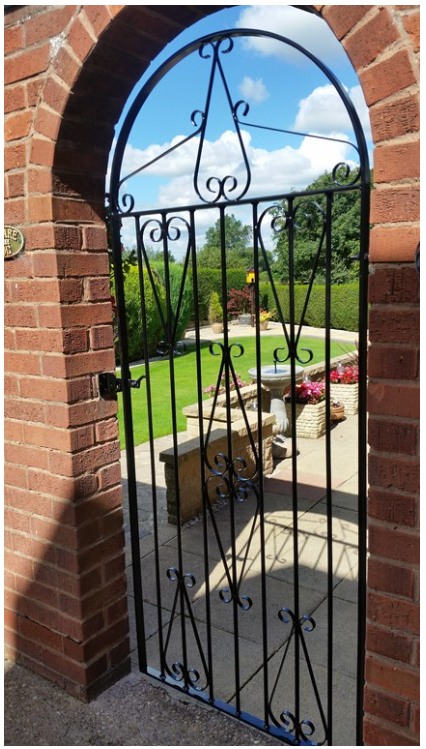 Arched wrought iron gate in matching brick wall