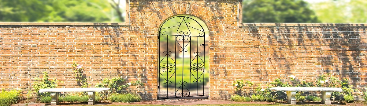 Arched wrought iron side gate installed into old brick wall